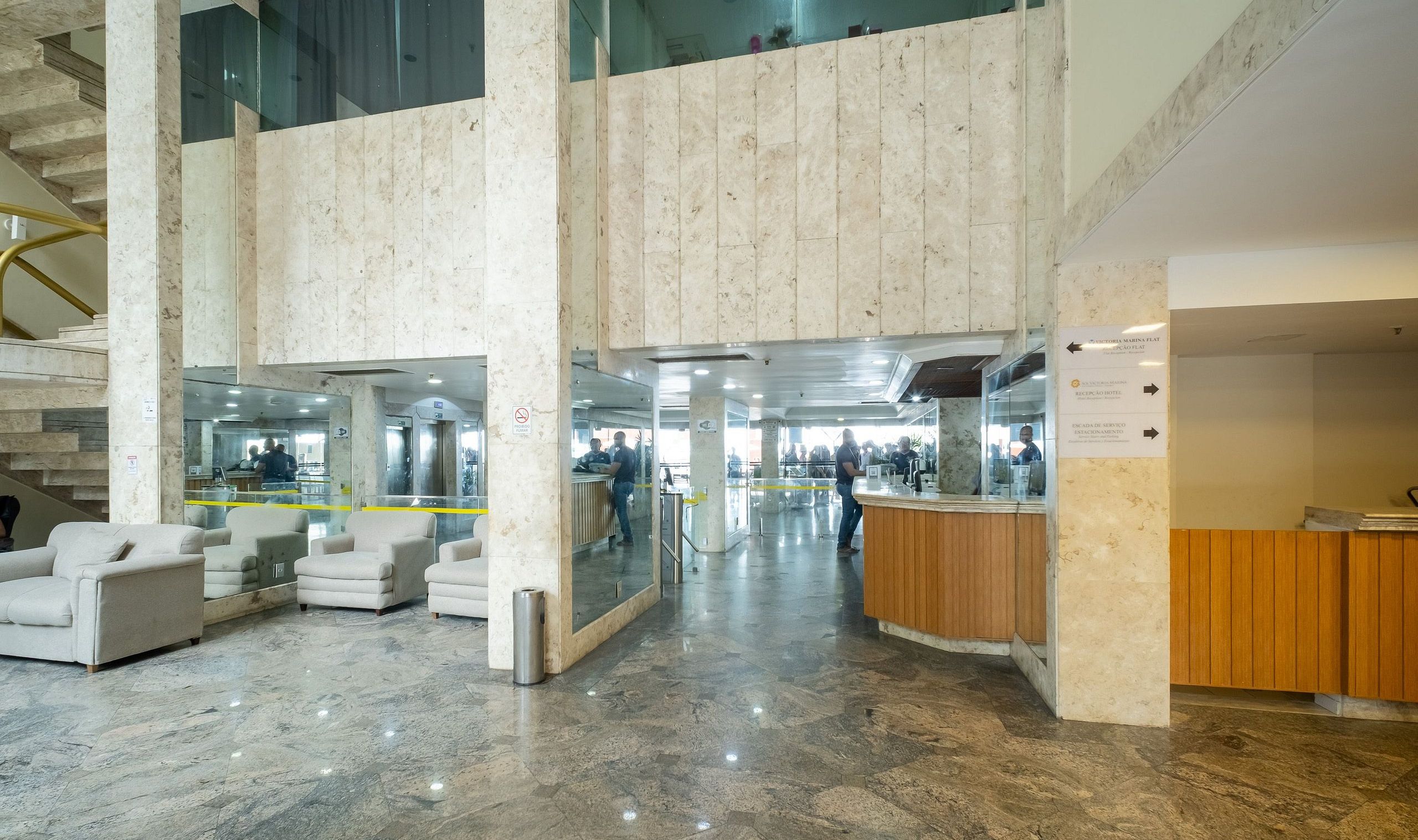 A spacious lobby with marble flooring, a reception desk, and seating areas.