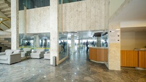 Un hall d’entrée spacieux, doté d’un sol en marbre, d’un comptoir de réception et d’un escalier.