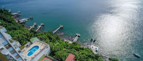 Ein Wohngebiet mit Swimmingpool, Tennisplatz und Blick auf das Meer mit Anlegestellen.