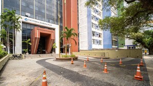 Appartement à Victoria Marina, avec une façade moderne, un hall d’entrée pavé et des palmiers environnants.