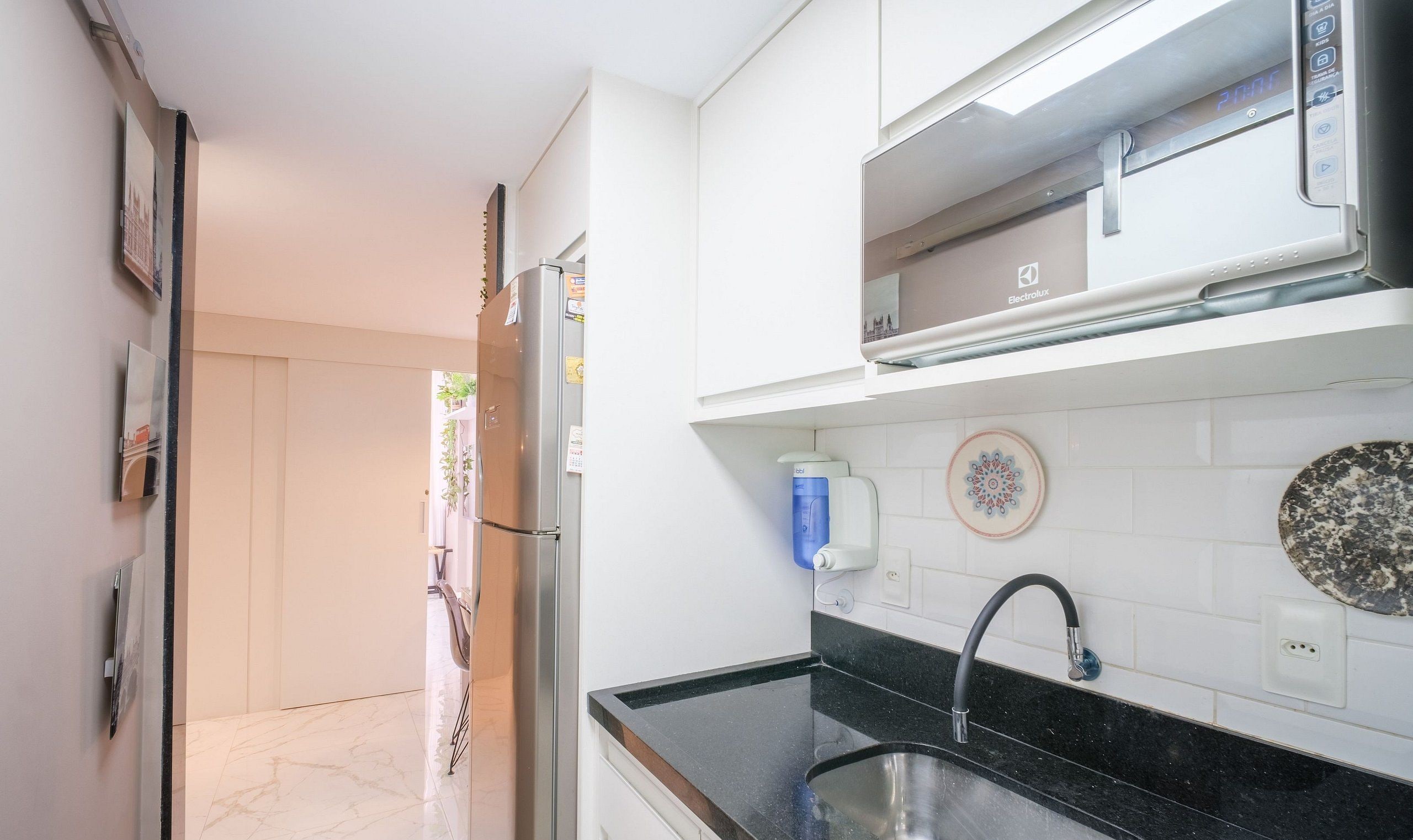 A modern kitchen with a black countertop, stainless steel sink, and a built-in oven.