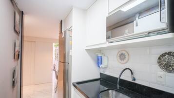 A modern kitchen with a black countertop, stainless steel sink, and a built-in oven.