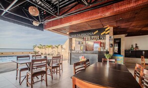 An outdoor bar area with a poolside seating arrangement, a bar counter with various bottles, and a view of the sea. - Sea View Apartment in Vitoria-ssa - Svm1409 (Salvador)