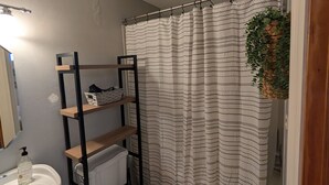 Ein Badezimmer mit Toilette, Waschbecken, Duschvorhang und Heizkörper.