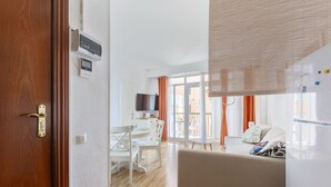 Un salon moderne avec un canapé, une table à manger et des chaises, ainsi qu’un téléviseur.