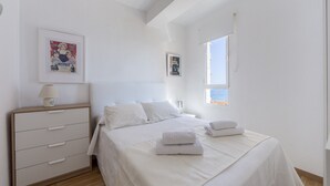 Une chambre à coucher avec un lit, une table de chevet, une commode et une fenêtre donnant sur un beau paysage.
