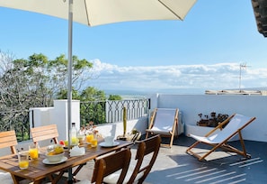Una terraza con una mesa lista para el desayuno, una silla y vista al mar.