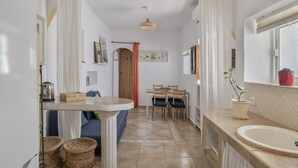 Una cocina con un lavamanos, una mesa de comedor, sillas y una planta en maceta.