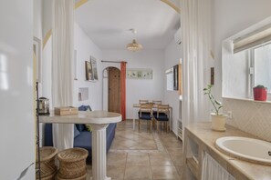 A kitchen with a sink, dining table, chairs, and a potted plant.