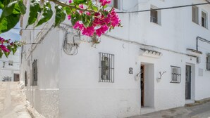 Un edificio blanco con ventanas de rejas, una puerta y un pequeño balcón.