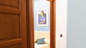 A hallway with a wooden door, a framed picture on the wall, a beige sofa, and a small white table. - Residence El Diez (Naples)