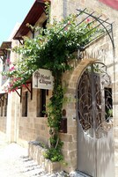 A stone building with a wrought iron gate and a sign for Hotel Ellique.