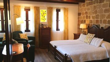Une chambre à coucher avec un grand lit, deux tables de chevet, une commode, une chaise, une table et des rideaux.