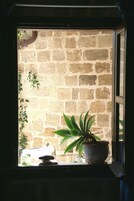 A window with a view of a stone wall and a potted plant.