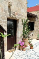 A stone building with a dark wooden door, potted plants, and a patterned floor.