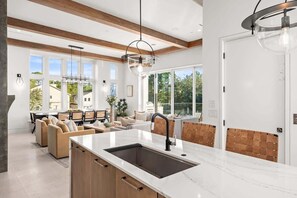 A modern kitchen with a large island, wooden beams, and large windows. - 30A Gulf View l Golf Cart l Pool l Rooftop Deck (Santa Rosa Beach)