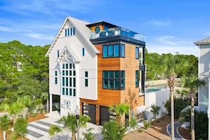 A modern two-story house with a large balcony, a swimming pool, and a well-maintained garden.