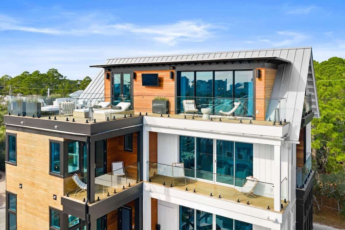 A modern multi-story building with a rooftop terrace featuring outdoor seating and a pool.