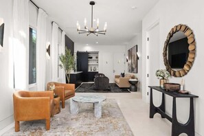Una sala de estar moderna con un sofá, sillones, una mesa de centro y un espejo grande.