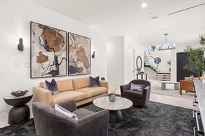 A modern living room with a sofa, armchairs, a coffee table, and abstract wall art.