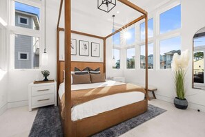 Un dormitorio con cama con dosel, una mesita de noche y un amplio ventanal.