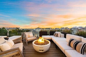 A deck with a fire pit, sofas, and a view of buildings in the background. - 30A Gulf View l Golf Cart l Pool l Rooftop Deck (Santa Rosa Beach)