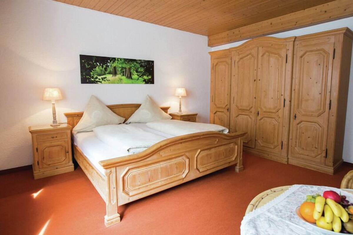 Ein Schlafzimmer mit einem hölzernen Bett, zwei Nachttischen mit Lampen, einem Kleiderschrank und einem gerahmten Bild an der Wand.