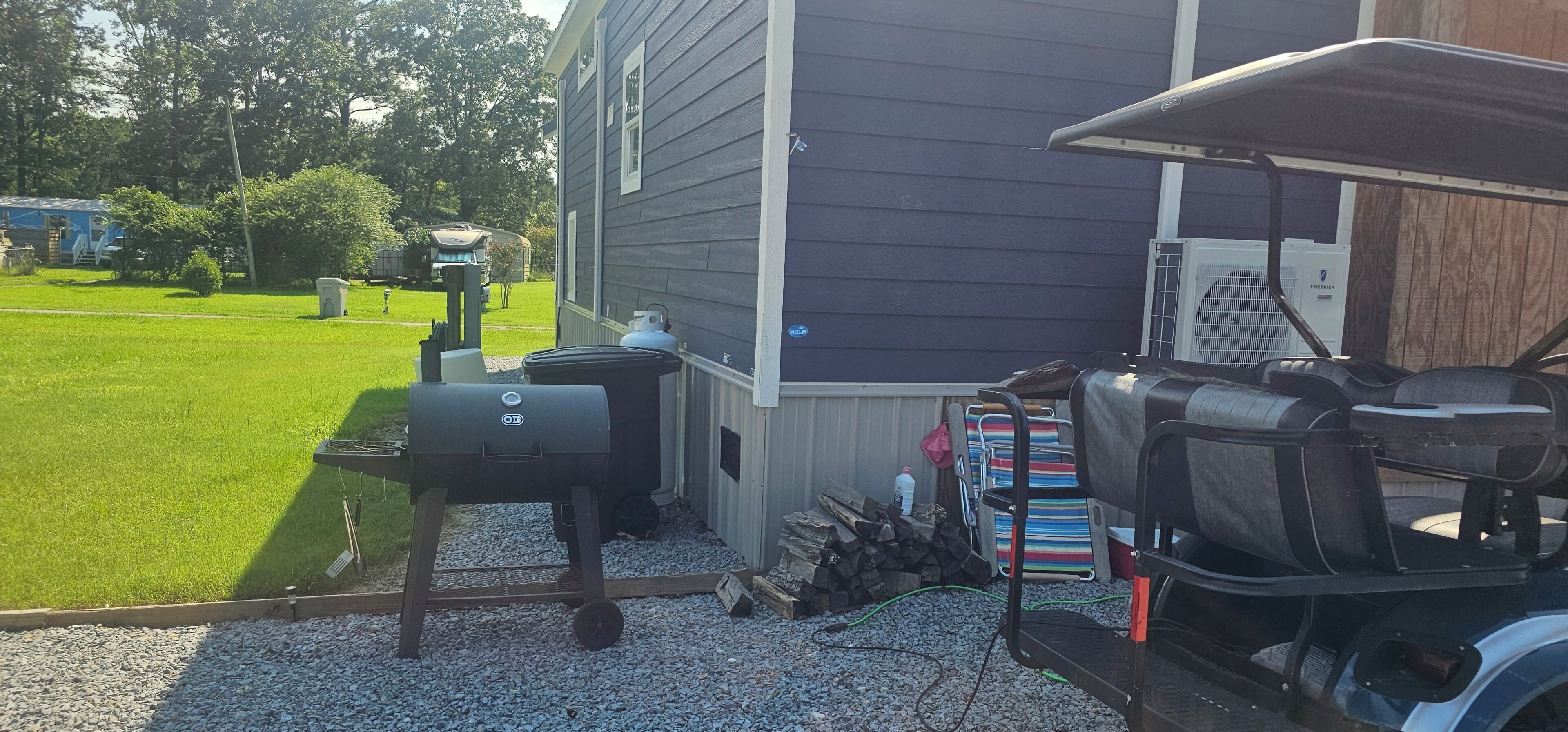 A backyard with a barbecue grill, a grill cover, and a grill cart.