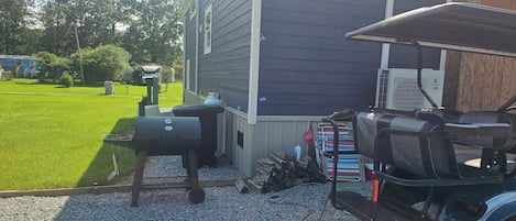 A backyard with a barbecue grill, a grill cover, and a grill cart.
