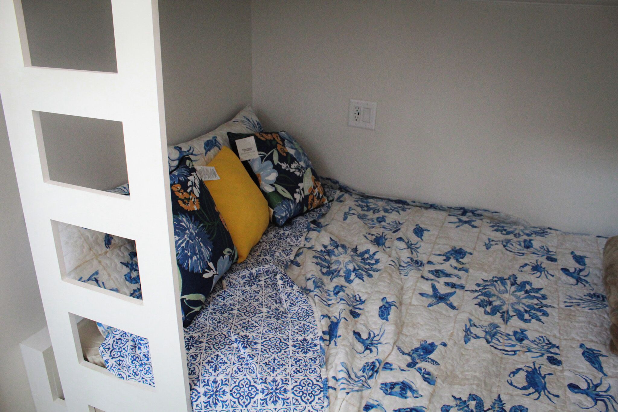 Ein kleines Zimmer mit einem Einzelbett, weißer Wand, Fenster und einer Tür mit weißem Rahmen.