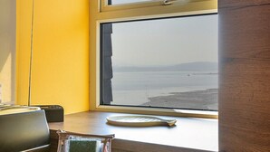 A kitchen with a wooden countertop, a window with a view of the sea, and a sink. - Beau View at Gadlys House (Beaumaris)