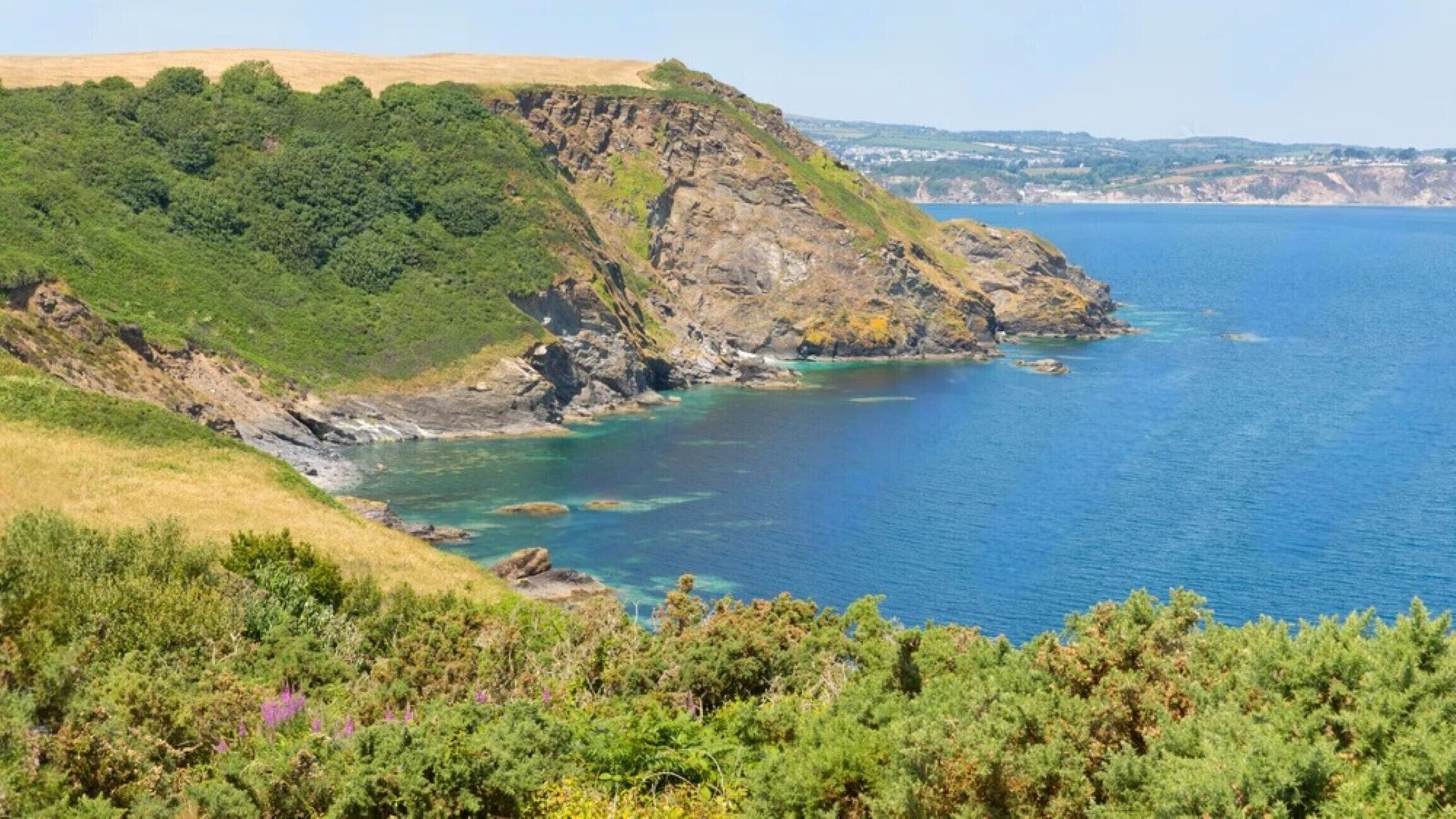 Un paysage côtier avec une falaise rocheuse et une mer bleue et limpide.