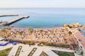 A beach resort with sun loungers, palm trees, and a view of the sea. - Elegant Escape in Egypt (Mer Rouge)