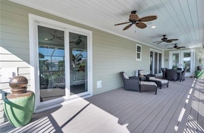 A covered outdoor area with ceiling fans, a sliding glass door, and outdoor furniture. - Sunset Breeze (Fort Myers Beach)
