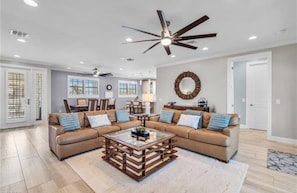 A spacious living room with a sectional sofa, a glass coffee table, and a ceiling fan. - Sunset Breeze (Fort Myers Beach)