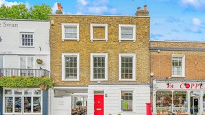 A row of traditional brick buildings with white facades, including a shop with a red door and another with a sign reading "Copp." - Palace Gate, Hampton Court (East Molesey)