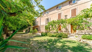 Une cour avec un bâtiment, des arbres et une zone herbeuse.