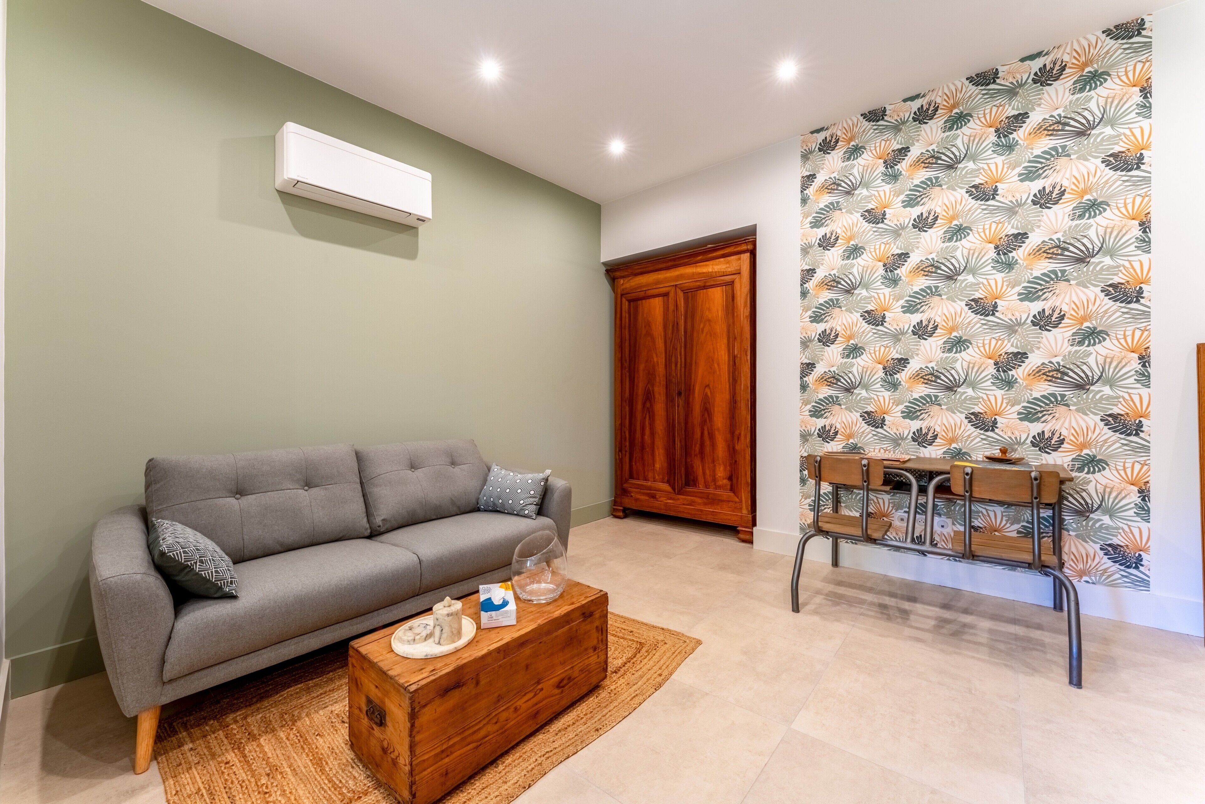 A living room with a grey sofa, wooden coffee table, and a patterned wall.