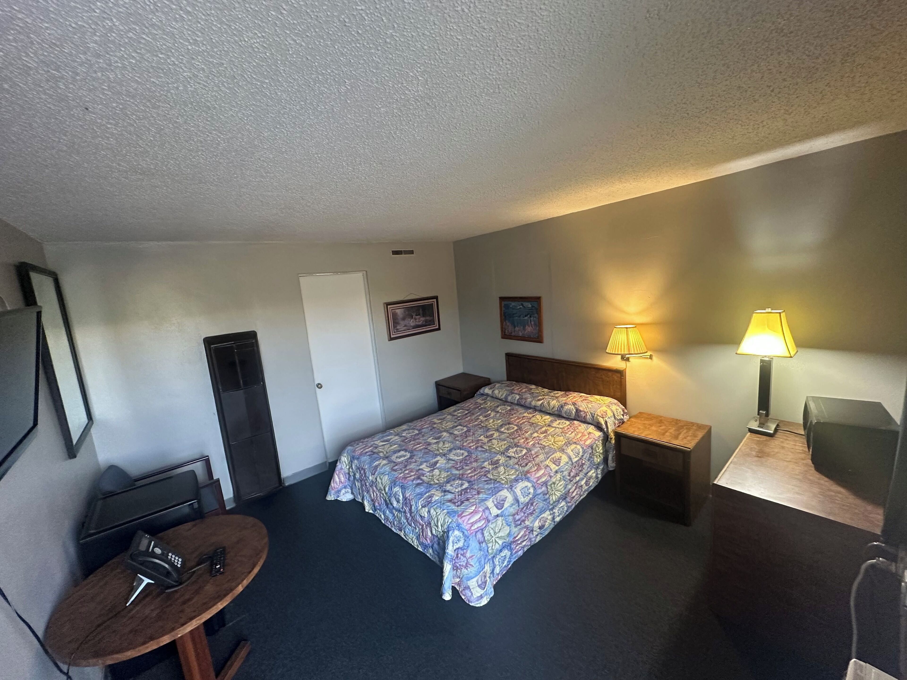 A hotel room with two beds, a desk, a chair, a lamp, and a TV.