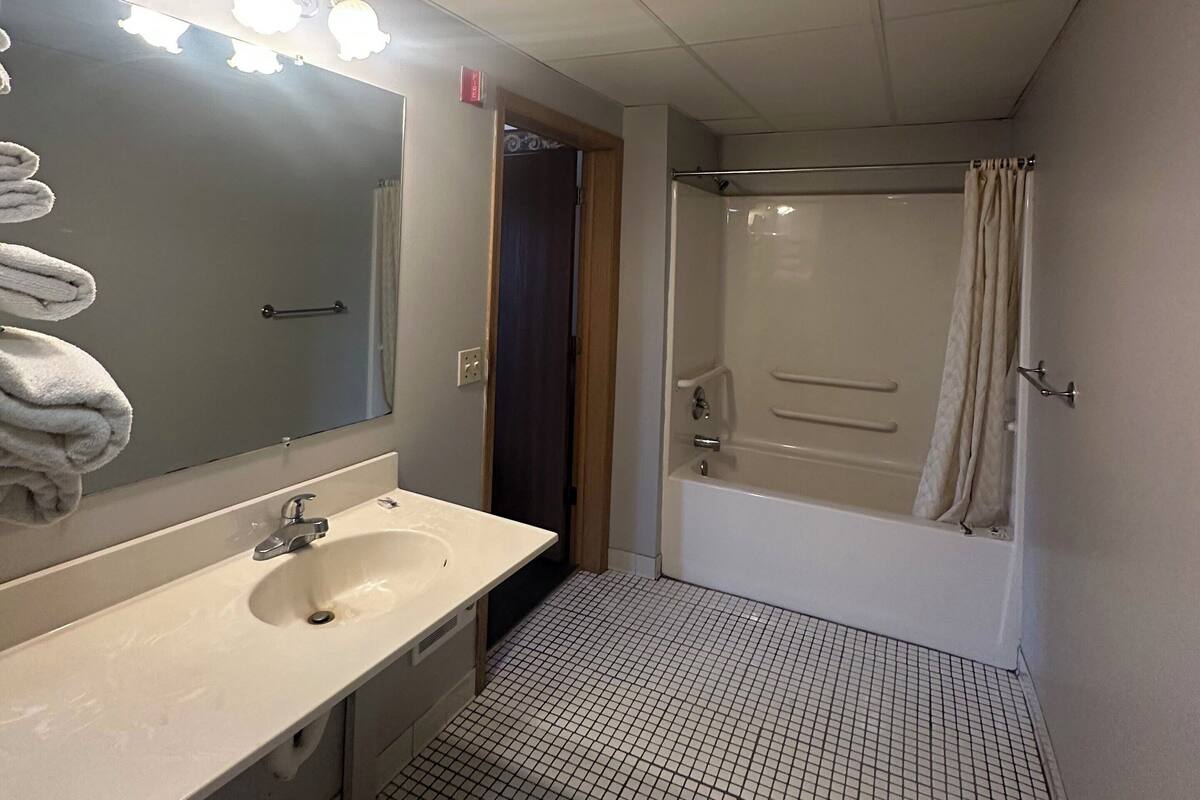 Un baño con lavamanos, espejo y ducha.
