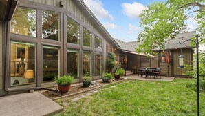 A modern building with large windows, a patio with outdoor seating, and potted plants. - Peaceful Pines | Home Gym & Office, Near Trails (Fort Collins)