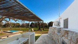 Un patio exterior con pared de piedra, piscina y pérgola.