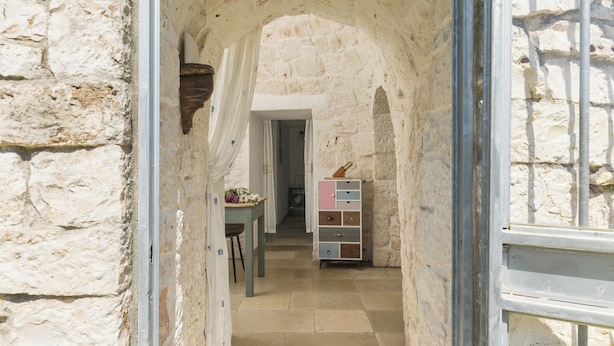 Un estrecho pasillo de piedra con una mesa de madera y un aparador colorido.