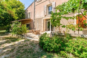 A building with a patio area, outdoor seating, and a garden. - Room 'Malo' with Shared Terrace, Shared Garden and Air Conditioning (Les Angles)