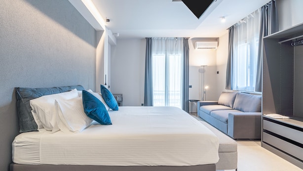 Una habitación de hotel moderna con una cama grande, un sofá, un televisor y un escritorio.