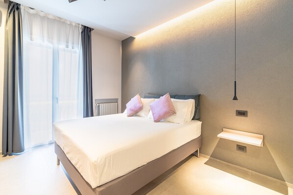 A modern bedroom with a large bed, bedside tables, and a built-in shelf. - Room 'Rosa' with Mountain View, Shared Terrace and Air Conditioning (Viagrande)