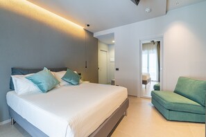 A modern bedroom with a bed, a green sofa, and a bathroom visible through an open door. - Room 'Verde' with Mountain View, Shared Terrace and Air Conditioning (Viagrande)