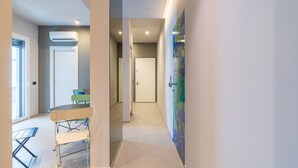 A hallway with a table and chairs, an air conditioning unit, and a door.