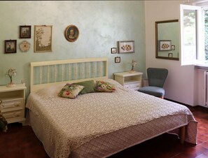 Une chambre à coucher comprenant un lit, des tables de chevet, une chaise et des œuvres d’art murales.