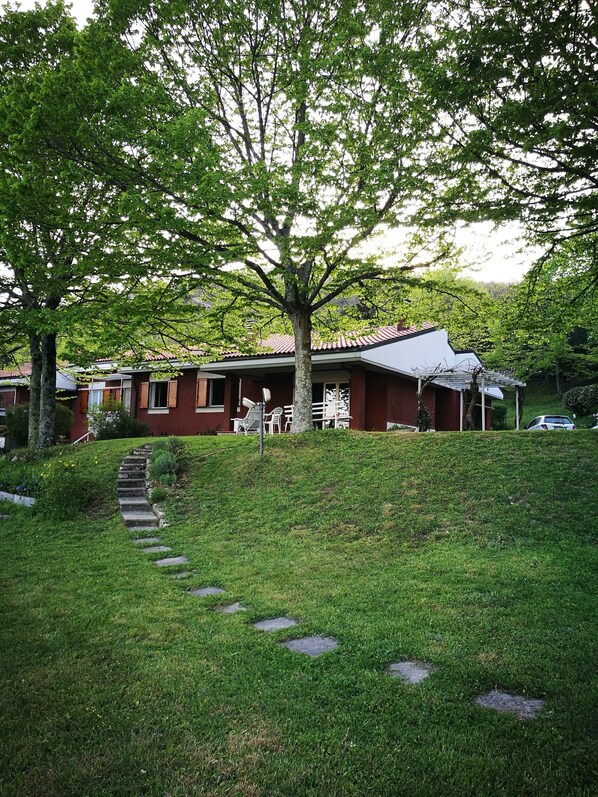 Ein Wohnhaus mit roten Backsteinen, ein großer Baum davor und ein Steinweg, der zum Eingang führt.